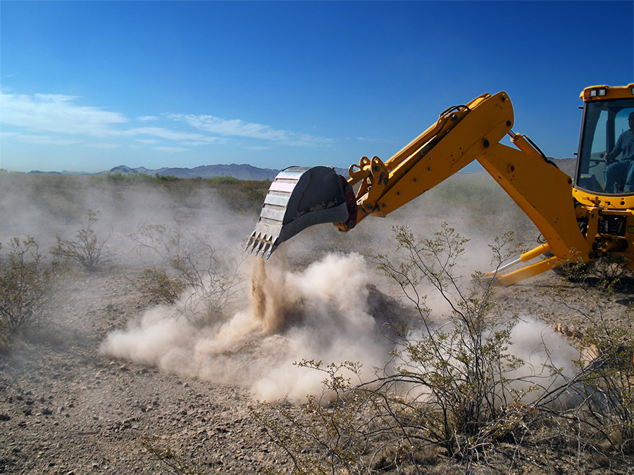 Image of an Excavator in the desert making dust